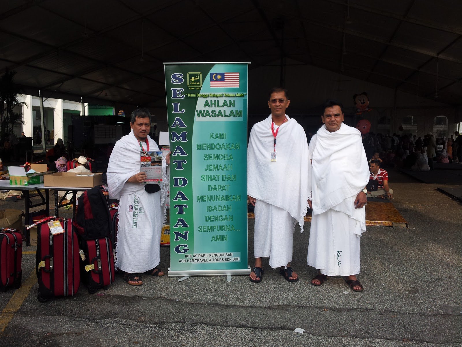 Dr. Abu Anas Madani dan dua jemaah berihram di sisi sepanduk Selamat Datang Ash-Har Travel